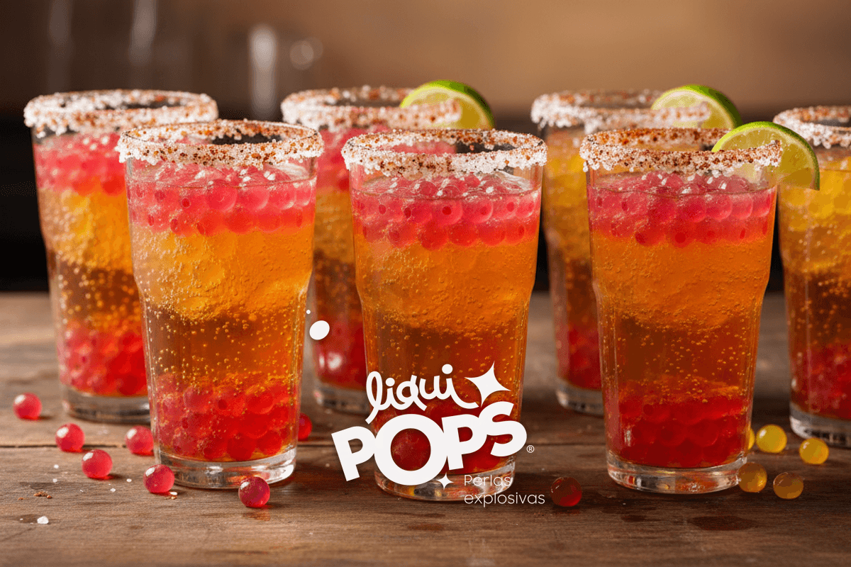 Catering scene: row of 6 michelada de soda glasses in line, ready for an event, salt rims and toppings consistent.